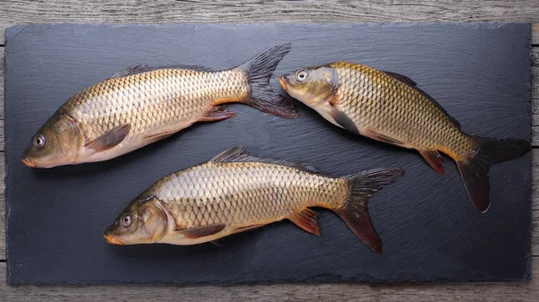 Fresh carps on black cutting board — Stock Photo, Image