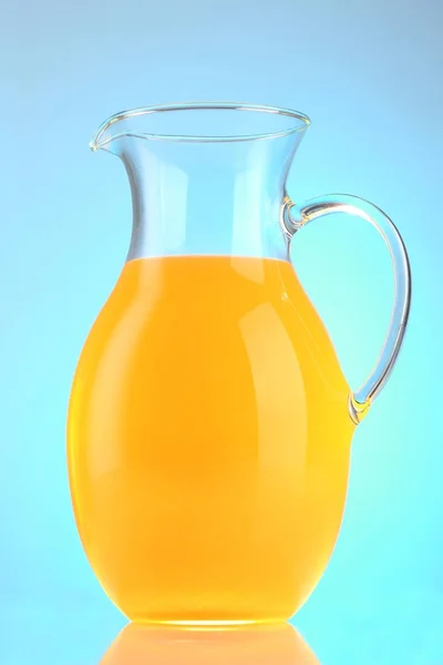 Jug of orange juice on blue background — Stock Photo, Image