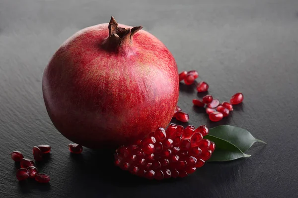 Pomegranate on black slate board — Stock Photo, Image