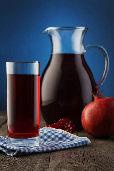 Glass and jar of pomegranate juice with fruit on blue — Stock Photo, Image
