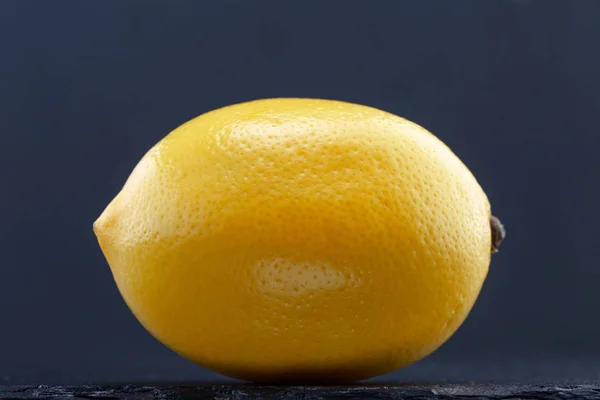 Лимон на черном камне на сером фоне — стоковое фото