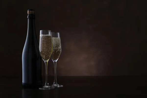 Butelka szampana i dwie szklanki na brązowym tle — Zdjęcie stockowe