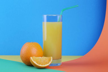 Parlak arkaplanda bir bardak portakal suyu ve portakal.