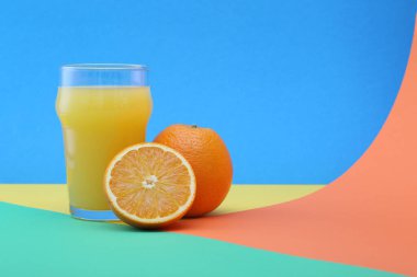 Parlak arkaplanda bir bardak portakal suyu ve meyve.