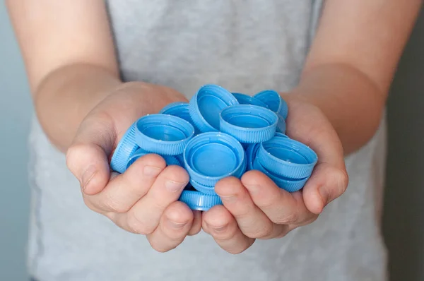 Plastik atık, dünya çevre günü, geri dönüşüm ve konsepti yeniden kullanma için beyaz zemin üzerinde izole edilmiş mavi plastik kapaklı Avrupalı erkek elleri.