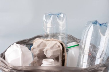 Plastik, ayıklanmış çöp, arka planda beyaz şişeler, kağıt, bardak gibi bir poşetin içinde yatıyor. Ekoloji konsepti, çöpleri ayırmak .