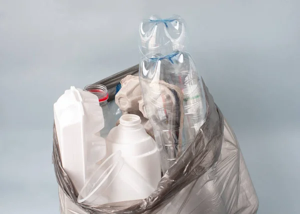 Plastik, ayıklanmış çöp, arka planda beyaz şişeler, kağıt, bardak gibi bir poşetin içinde yatıyor. Ekoloji konsepti, çöpleri ayırmak .