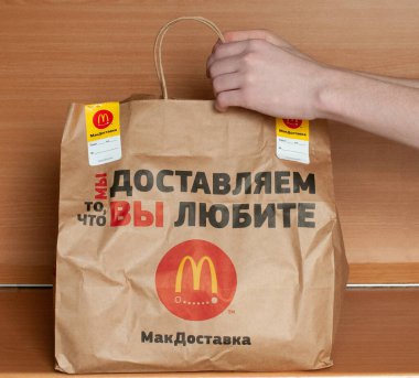Rusya, Moskova Nisan 2020: masada McDonalds için bir paket kâğıt çanta var, alıcı ev yemeği olarak aldı. Ürünün dağıtım konsepti Illustrative Editorial picture.