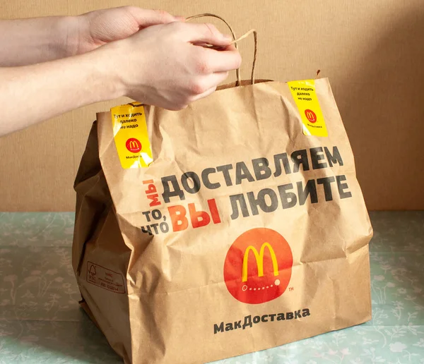 Rusya, Moskova Nisan 2020: masada McDonalds için bir paket kâğıt çanta var, alıcı ev yemeği olarak aldı. Ürünün dağıtım konsepti Illustrative Editorial picture.