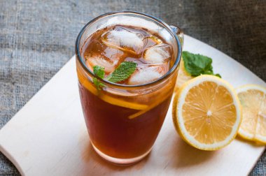 Bardakta siyah buzlu çay, tahtanın üzerinde sarı dilimlenmiş limon. Sağlıklı beslenme kavramı.