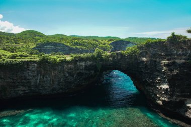 Kaya kıyı şeridi ve taş kemer Nusa Penida 'daki kırık plaj denizi üzerinde