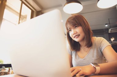 Kafede dizüstü bilgisayarıyla çalışan Asyalı bir kadın..