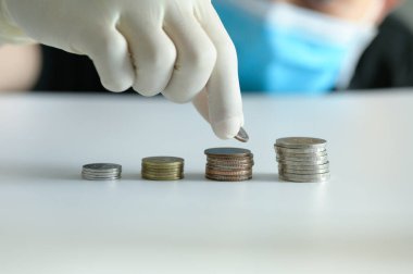 Tıbbi maskeli bir erkek para yığını, konsept iş, finans, tasarruf, Coronavirus küresel ekonomi borsaları mali kriz etkiler