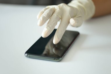 Tıbbi eldivenli el seçici odaklı akıllı telefona dokunuyor