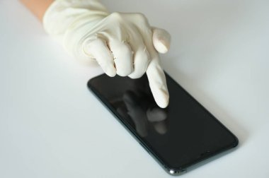 Tıbbi eldivenli el seçici odaklı akıllı telefona dokunuyor