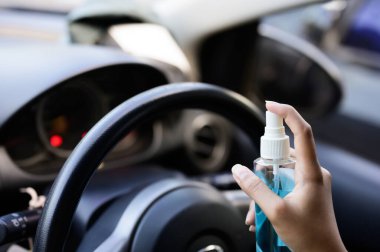 Şoförün eli arabaya alkol, dezenfektan spreyi sıkıyor. Emniyet, Covid 19 virüsü, koronavirüs enfeksiyonu, mikrop ya da bakteri bulaşmasını önlüyor. Alkol dezenfektanı, hijyen konsepti.