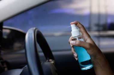 Şoförün eli arabaya alkol, dezenfektan spreyi sıkıyor. Emniyet, Covid 19 virüsü, koronavirüs enfeksiyonu, mikrop ya da bakteri bulaşmasını önlüyor. Alkol dezenfektanı, hijyen konsepti.