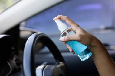 Şoförün eli arabaya alkol, dezenfektan spreyi sıkıyor. Emniyet, Covid 19 virüsü, koronavirüs enfeksiyonu, mikrop ya da bakteri bulaşmasını önlüyor. Alkol dezenfektanı, hijyen konsepti.