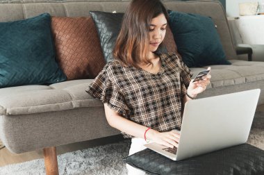 Genç Asyalı kadın kredi kartını evinde online alışveriş için kullanıyor.