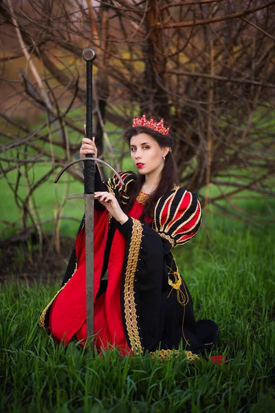 Привлекательная Девушка Черно Красном Средневековом Платье Короной Голове Мечом Руках — стоковое фото