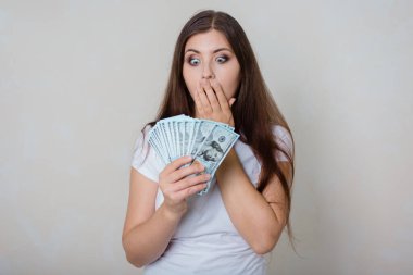 Beyaz tişörtlü, genç, güzel bir kadın. Elinde para, beyaz bir arka planda izole edilmiş..