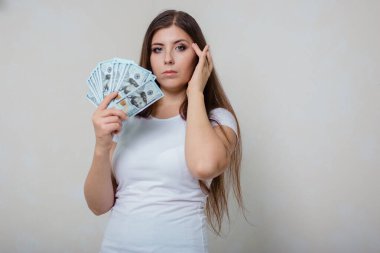 Beyaz tişörtlü, genç, güzel bir kadın. Elinde para, beyaz bir arka planda izole edilmiş..