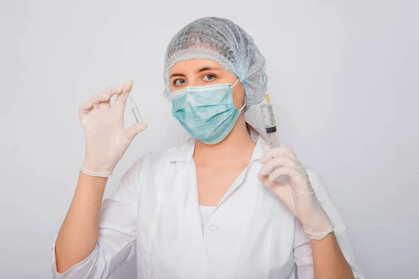 医生拿着注射器和带有疫苗的安培剂 身穿白衣 戴着医疗面具 头戴帽子 头戴手套 背景为白色的年轻女子 实验室医务工作者 Coronavirus疫苗搜索概念 — 图库照片