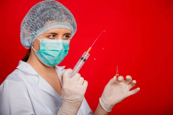 Kırmızı Arka Planda Bir Kadın Doktorun Elinde Bulunan Iğnenin Şırıngasını — Stok fotoğraf