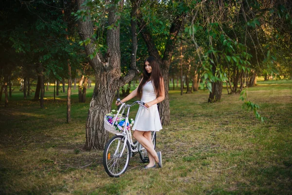 Девушка Белой Юбке Жилете Велосипедом Корзиной Цветов Парке Вечером — стоковое фото