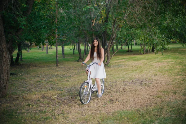 Menina Vestido Branco Monta Uma Bicicleta Através Parque Noite — Fotografia de Stock