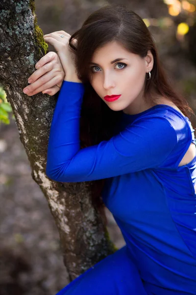 Όμορφη Νεαρή Γυναίκα Ένα Μπλε Φόρεμα Κάθεται Κοντά Ένα Δέντρο — Φωτογραφία Αρχείου