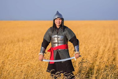 Doğulu bir savaşçı kılıçlı ve miğferli. 16. ve 18. yüzyıldan kalma. Buğday tarlasında dizlerine kadar duruyor..