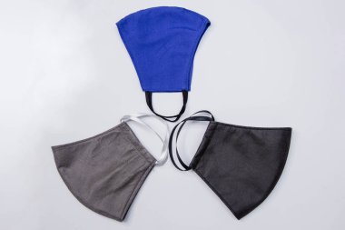 Farklı renklerde üç el yapımı tıbbi maske. Beyaz arka planda siyah, mavi ve gri izole edilmiş. Tıbbi maske kıtlığı ve el yapımı maskelerin popülerleştirilmesi..