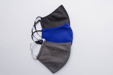 Farklı renklerde üç el yapımı tıbbi maske. Beyaz arka planda siyah, mavi ve gri izole edilmiş. Tıbbi maske kıtlığı ve el yapımı maskelerin popülerleştirilmesi..