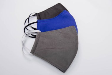 Farklı renklerde üç el yapımı tıbbi maske. Beyaz arka planda siyah, mavi ve gri izole edilmiş. Tıbbi maske kıtlığı ve el yapımı maskelerin popülerleştirilmesi..