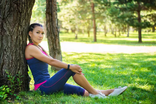 Sportieve Vrouw Zittend Het Gras Leunend Tegen Een Boom Het — Stockfoto