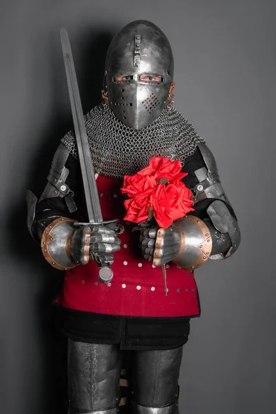 一个身穿盔甲的中世纪战士手里拿着剑和花 骑士送一束玫瑰 — 图库照片
