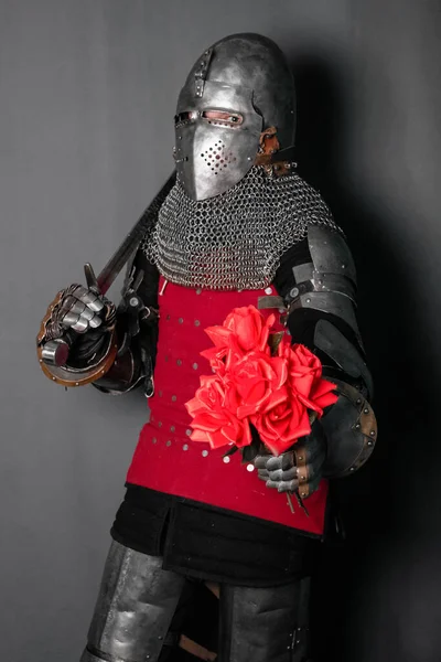 一个身穿盔甲的中世纪战士手里拿着剑和花 骑士送一束玫瑰 — 图库照片
