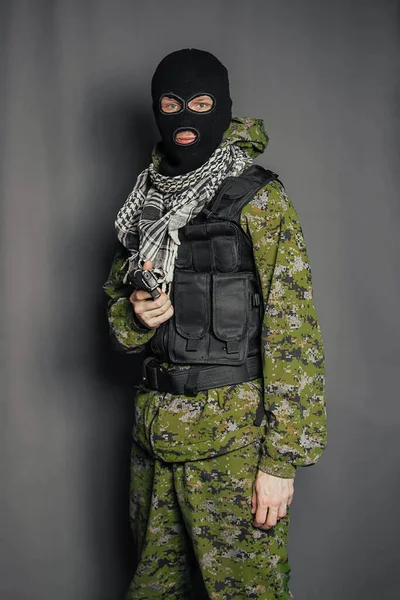 A member of the special police squad, takes aim, holds a pistol. Dressed in a balaclava, camouflage uniform, bulletproof vest. Special weapons and tactics. Special Forces.SWAT.