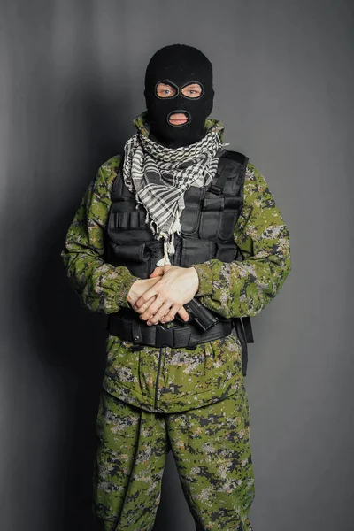 A member of the special police squad, takes aim, holds a pistol. Dressed in a balaclava, camouflage uniform, bulletproof vest. Special weapons and tactics. Special Forces.SWAT.