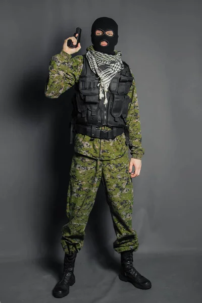 A member of the special police squad, takes aim, holds a pistol. Dressed in a balaclava, camouflage uniform, bulletproof vest. Special weapons and tactics. Special Forces.SWAT.