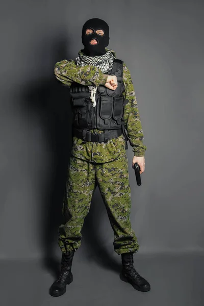 A member of the special police squad, takes aim, holds a pistol. Dressed in a balaclava, camouflage uniform, bulletproof vest. Special weapons and tactics. Special Forces.SWAT.