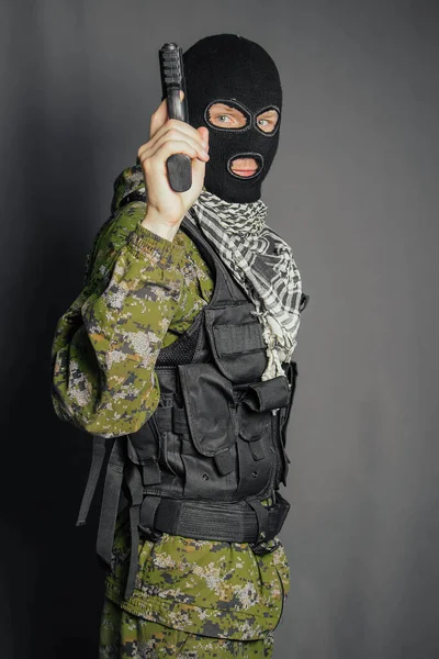 A member of the special police squad, takes aim, holds a pistol. Dressed in a balaclava, camouflage uniform, bulletproof vest. Special weapons and tactics. Special Forces.SWAT.