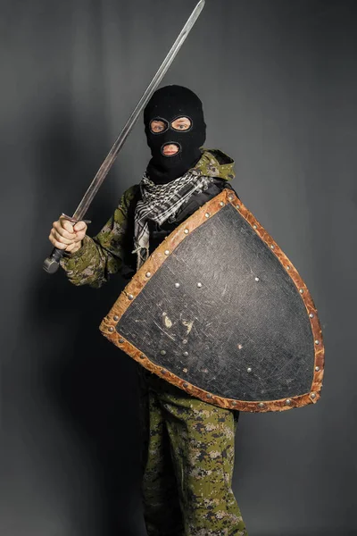 Modern warrior with medieval weapons in his hands. A soldier defends himself with a shield and attacks with a sword. Protection of law, law, order, property, money, peace of mind.