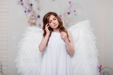 Arkasında kanatları olan beyaz elbiseli genç bir melek..