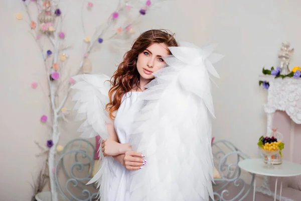 一个穿着白衣的天使站在用翅膀包裹着的年轻女子的画像 — 图库照片