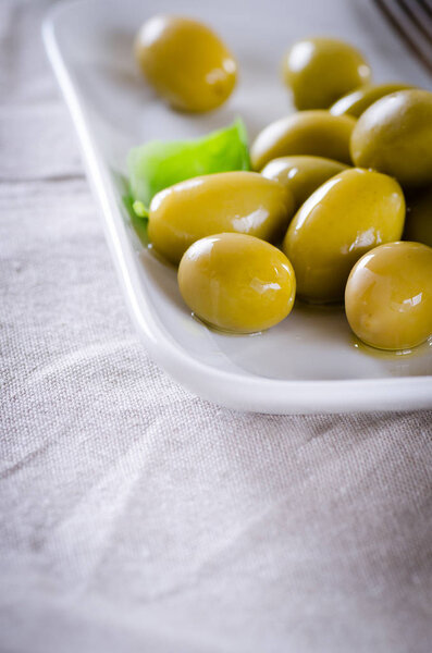 Green olives on a white plate