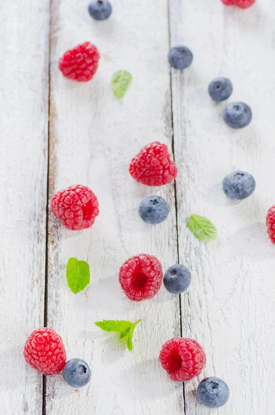 Raspberries and blueberries on white wooden background — Stock Photo, Image