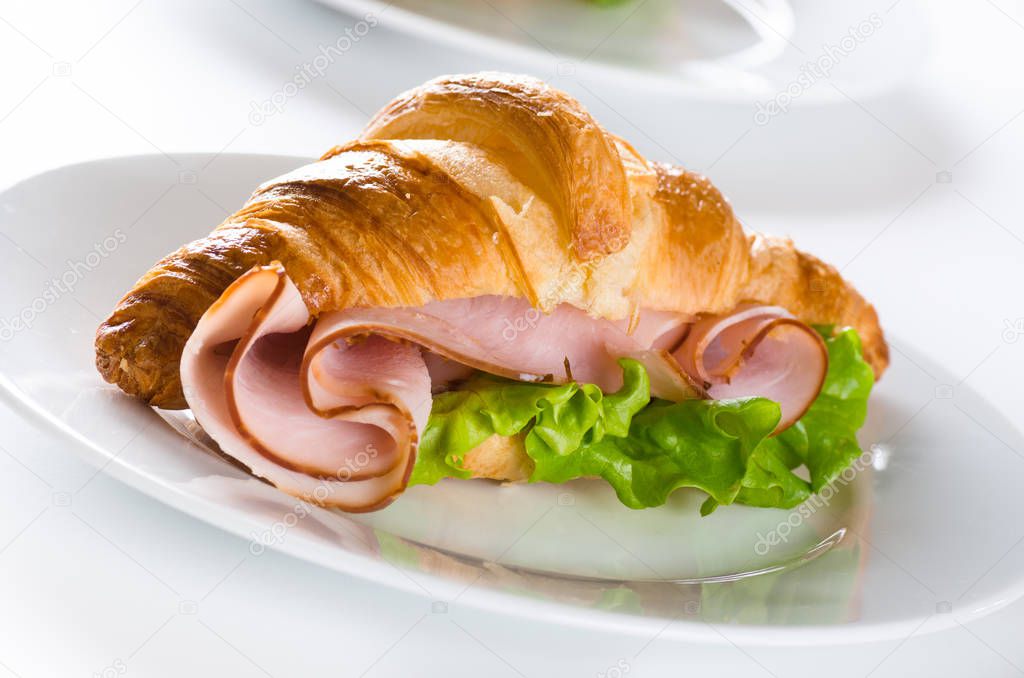 delicious fresh croissant with ham and lettuce 