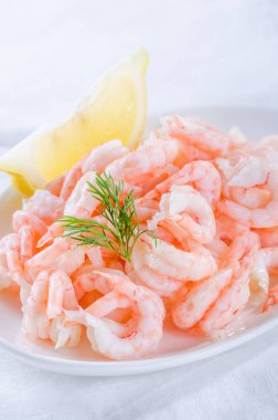 pişmiş karides ve beyaz plaka üzerinde limon dilimi ile soyulmuş